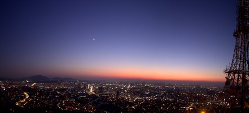 cityscape at dusk with crescent moon