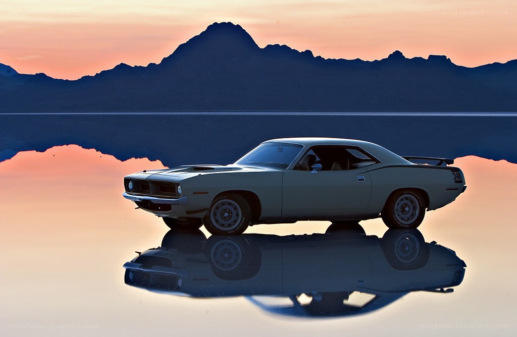 Classic car on salt flat at sunset