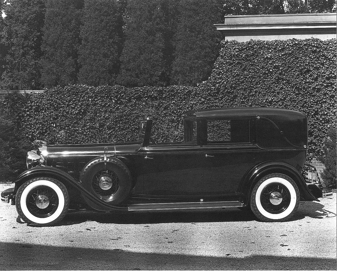 Classic car parked by hedge