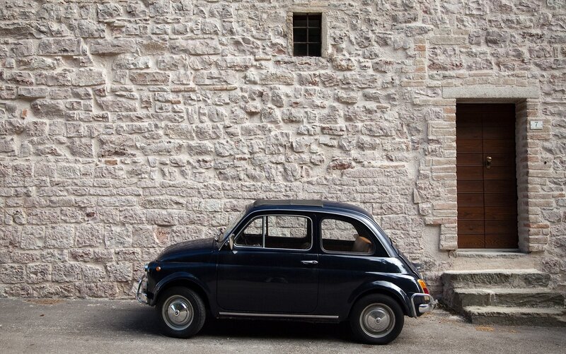 Classic car parked by stone wall
