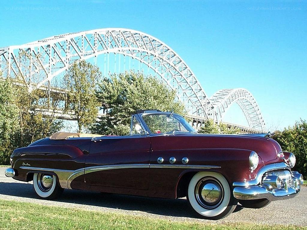Classic maroon convertible by a bridge
