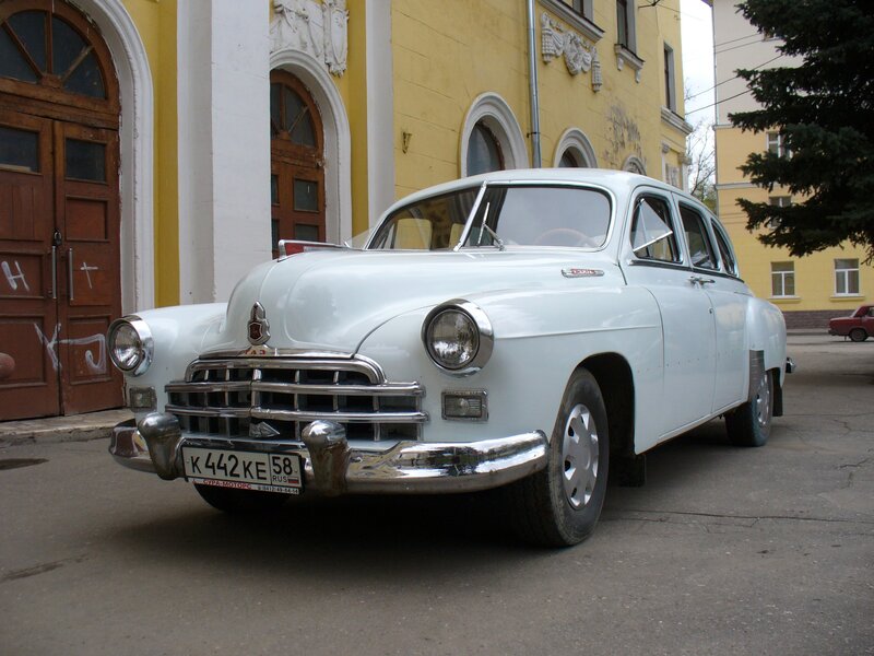 Classic white car parked in front of building
