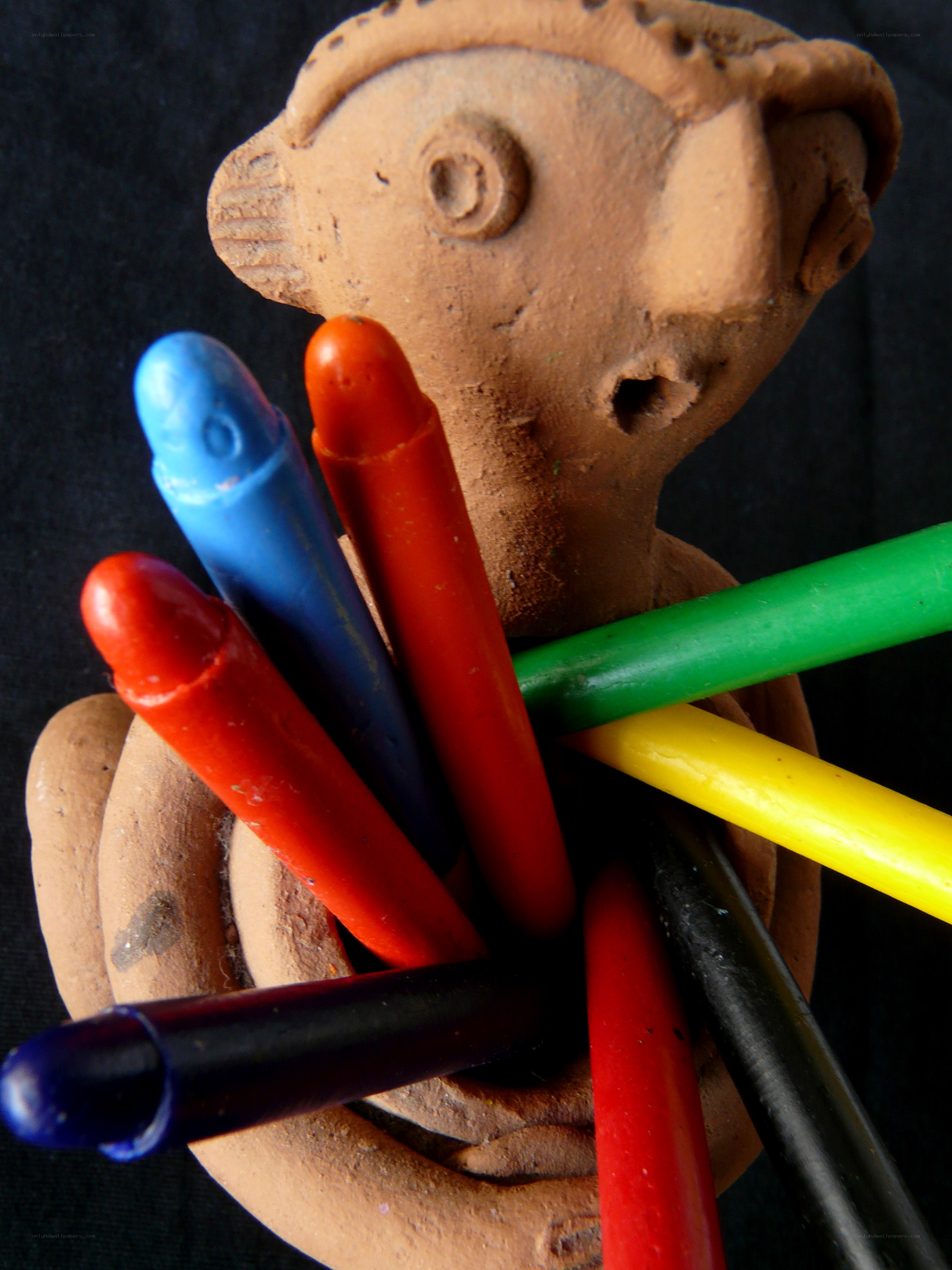 clay figure holding crayons