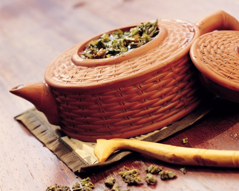 Clay teapot with green tea leaves