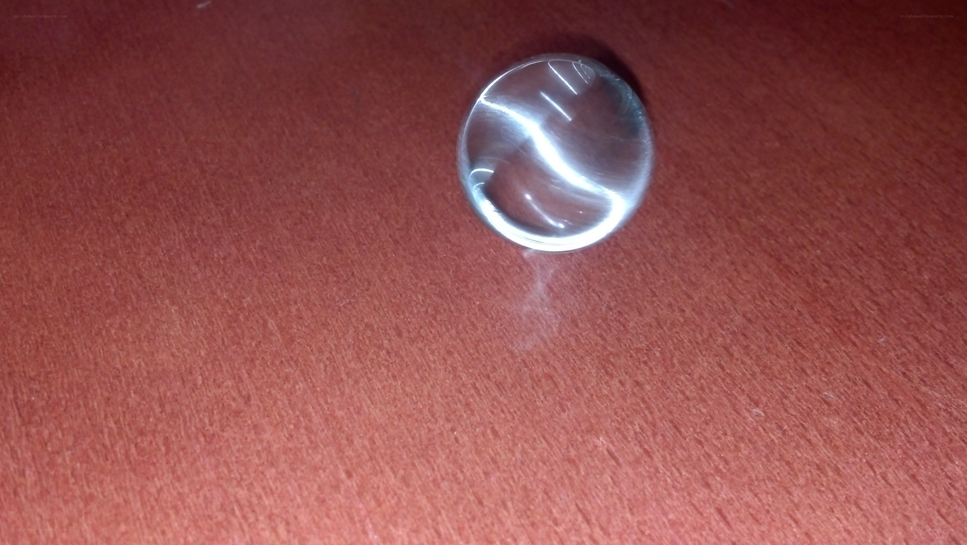 Clear glass marble on red surface