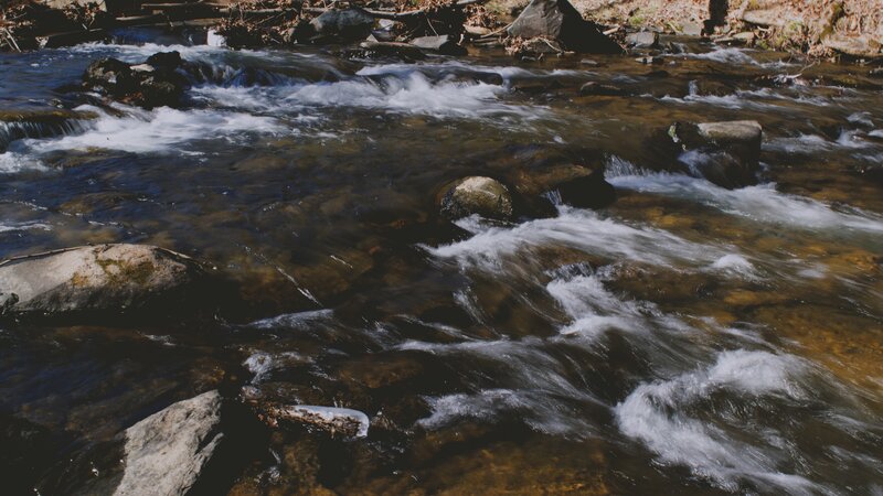Clear Stream Flowing over Rocks — Brown