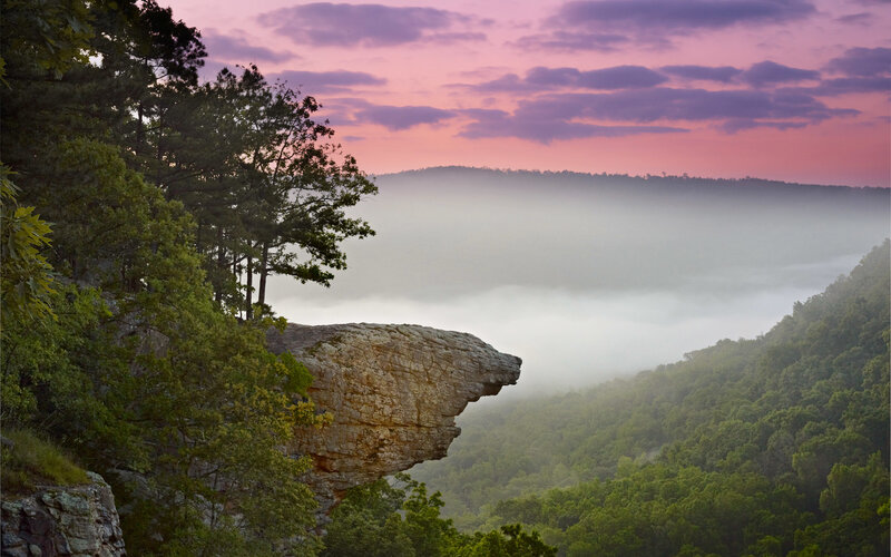 Cliff overlooks misty valley at dawn