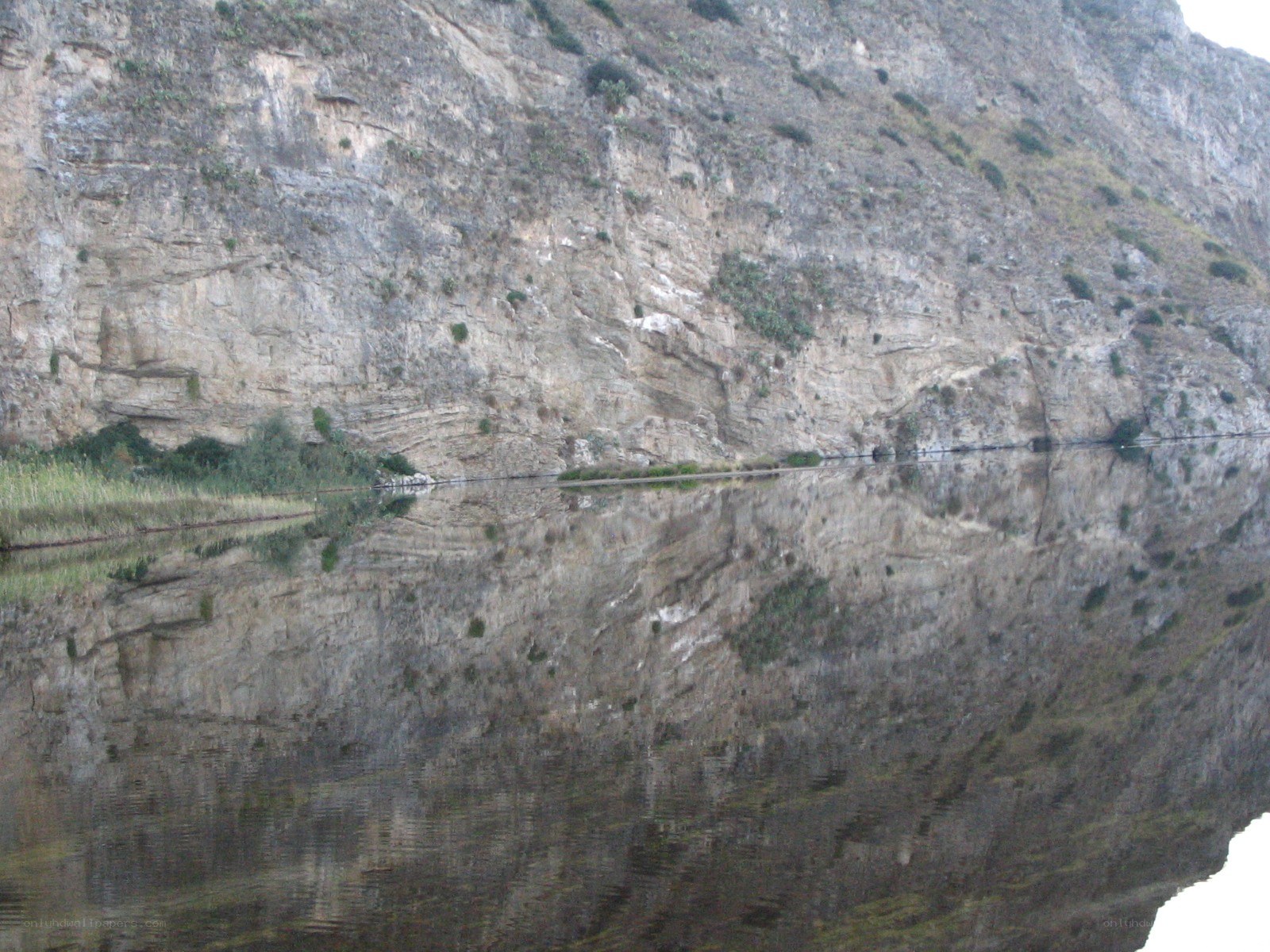 cliff reflected in calm water