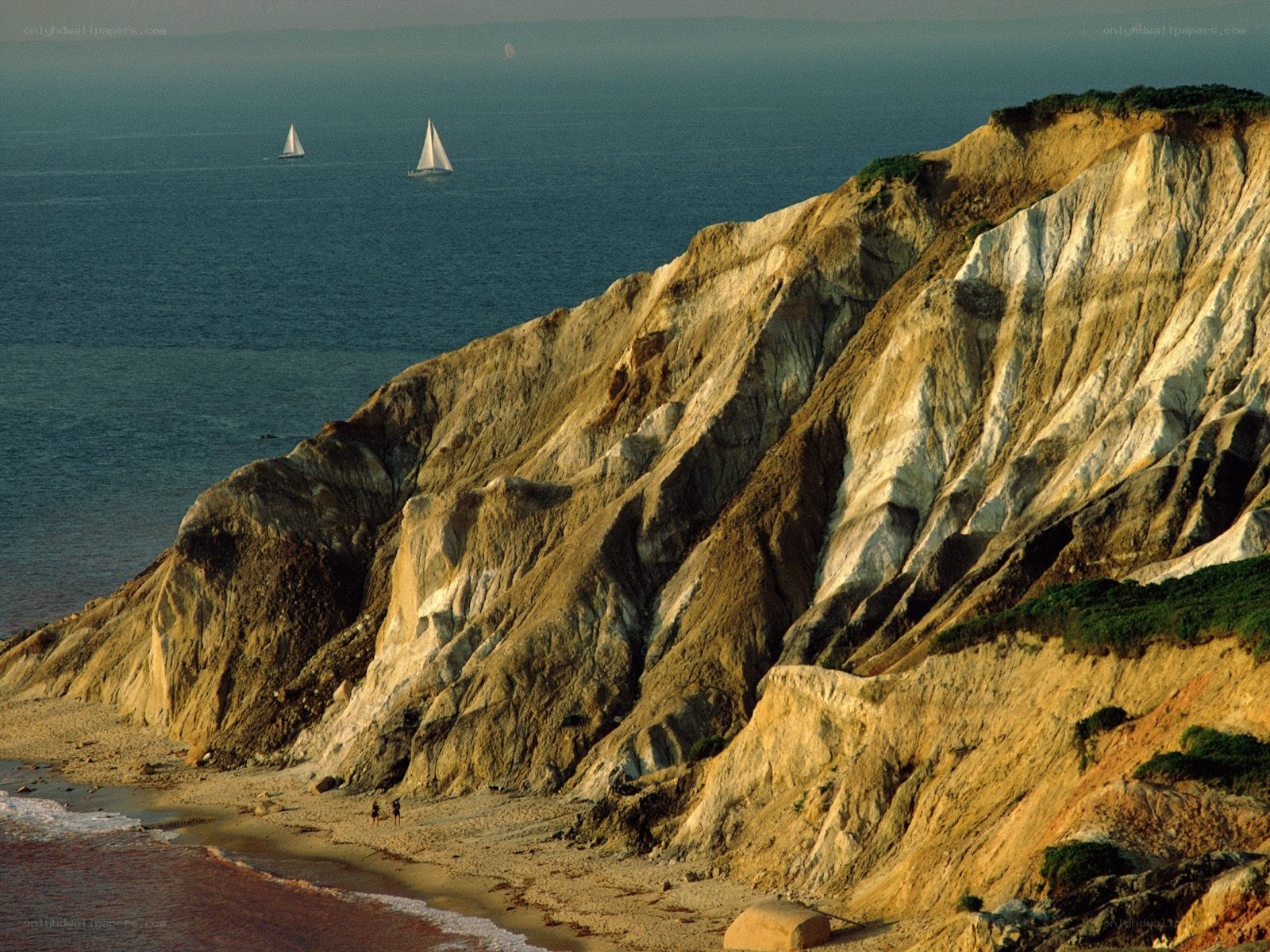 Cliffs and sailboats at sunset