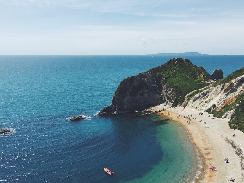Cliffside Beach Cove — Blue, Serene, Afternoon, Photograph, Ocean, Boat