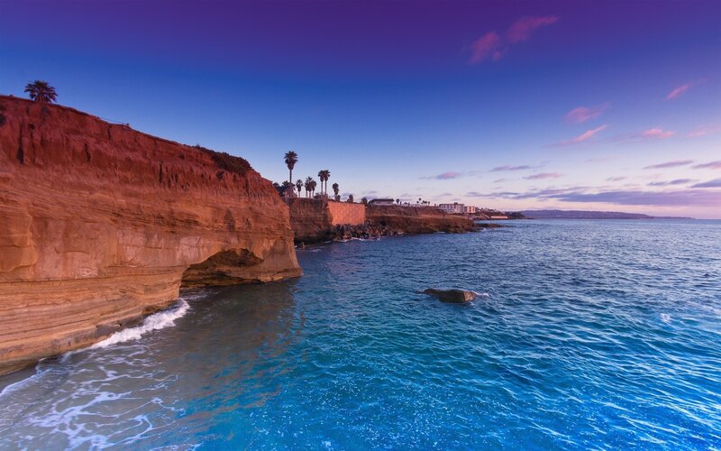 Cliffside Coastline — Blue, Serene, Sunset, Photograph, Ocean, Palm Trees, Rock Formations, Purple