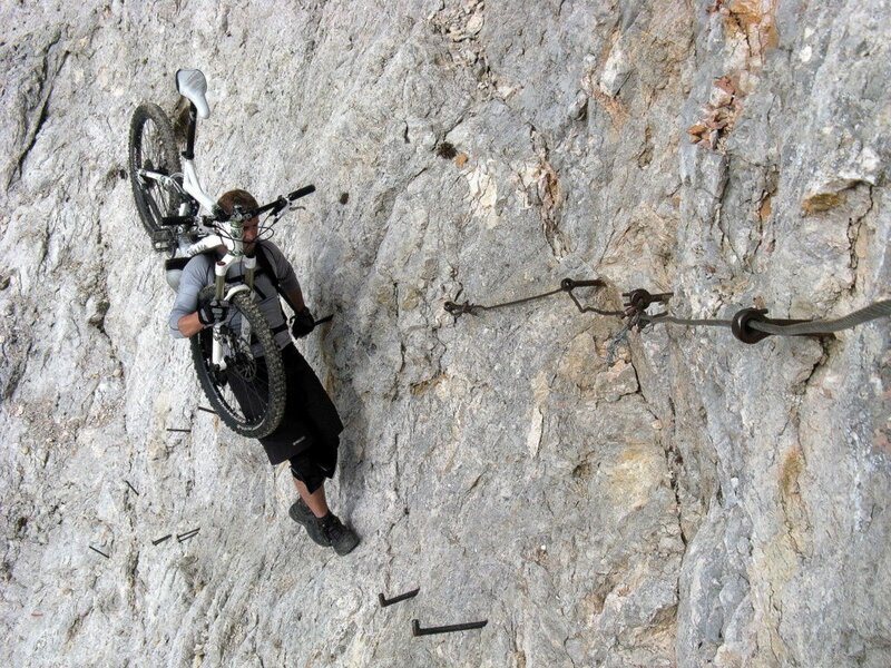 Climber carrying bike on rock face