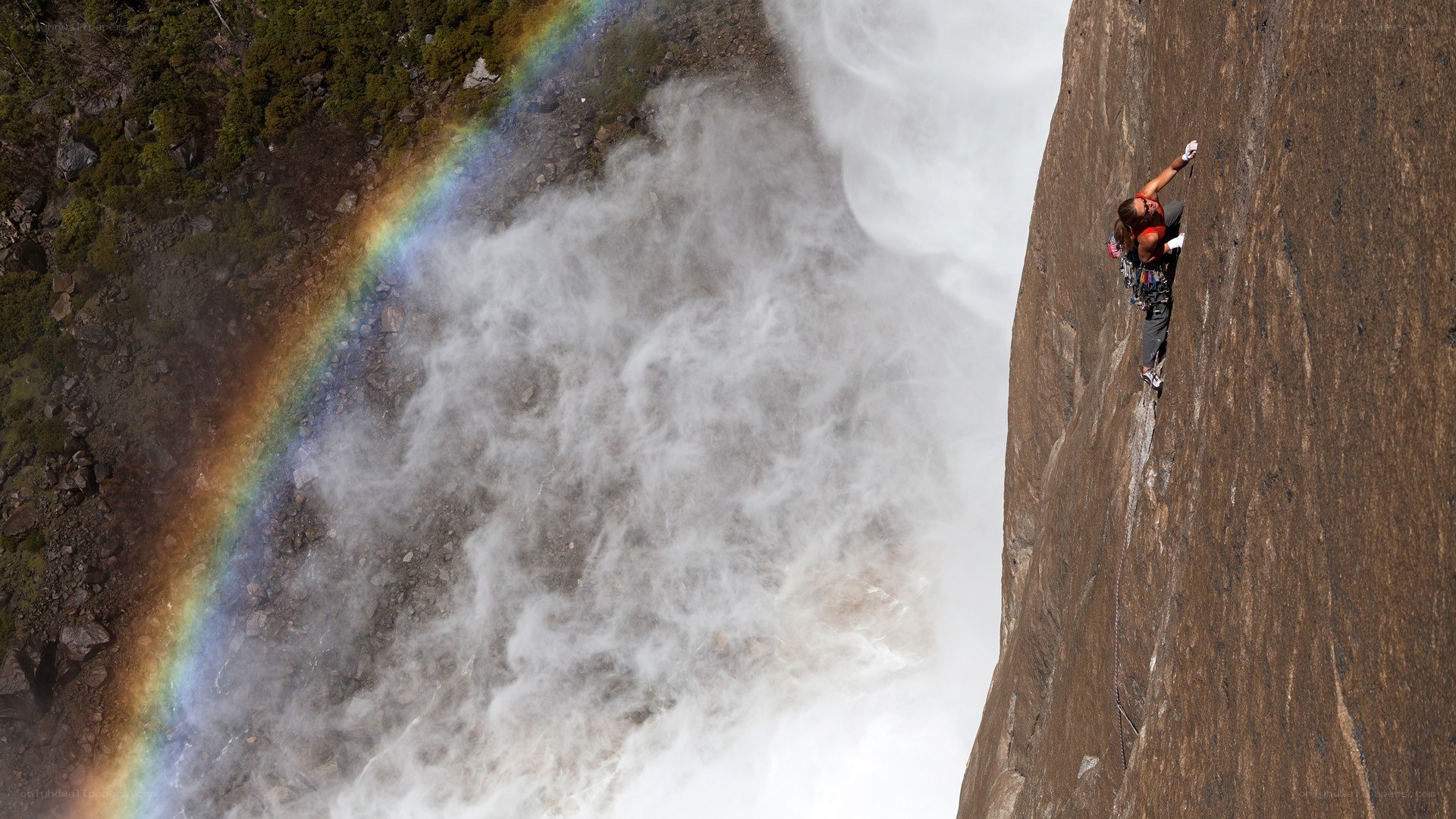 Climber near waterfall with rainbow