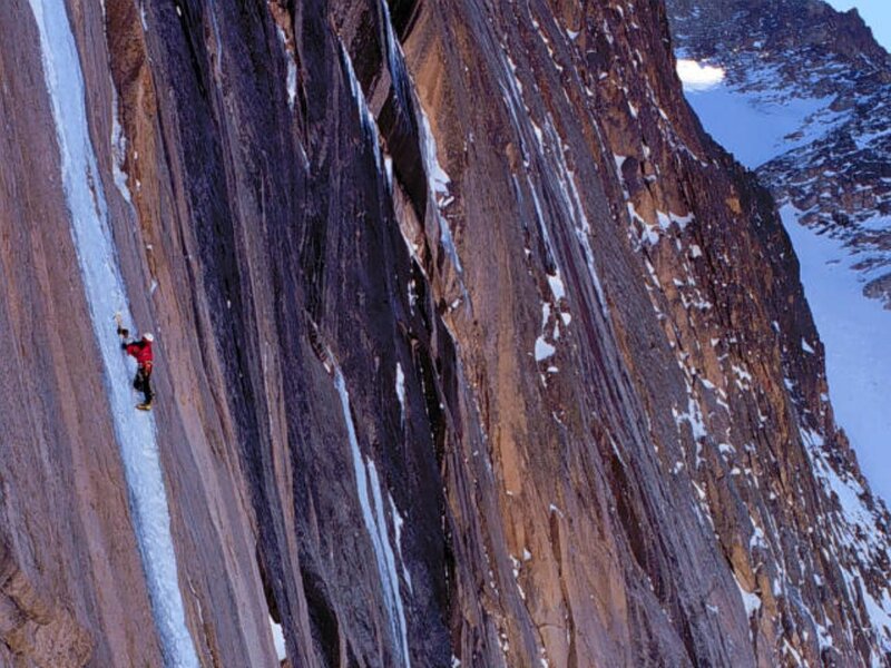 Climber on icy cliff face