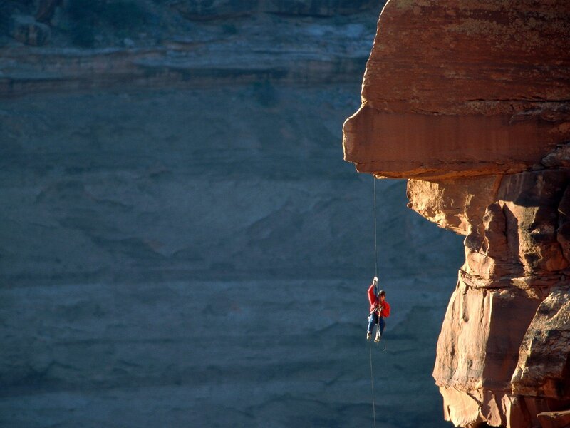 Climber rappelling down canyon