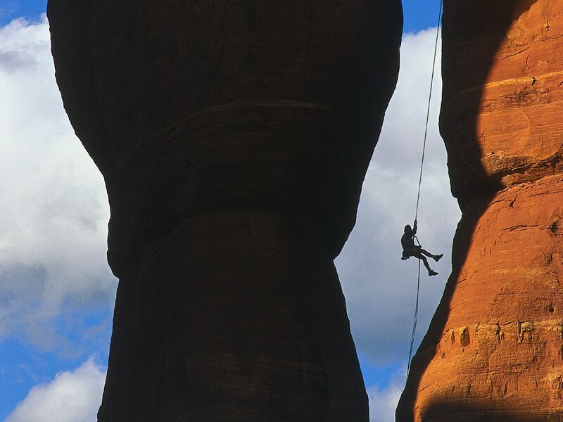 Climber rappelling in canyon