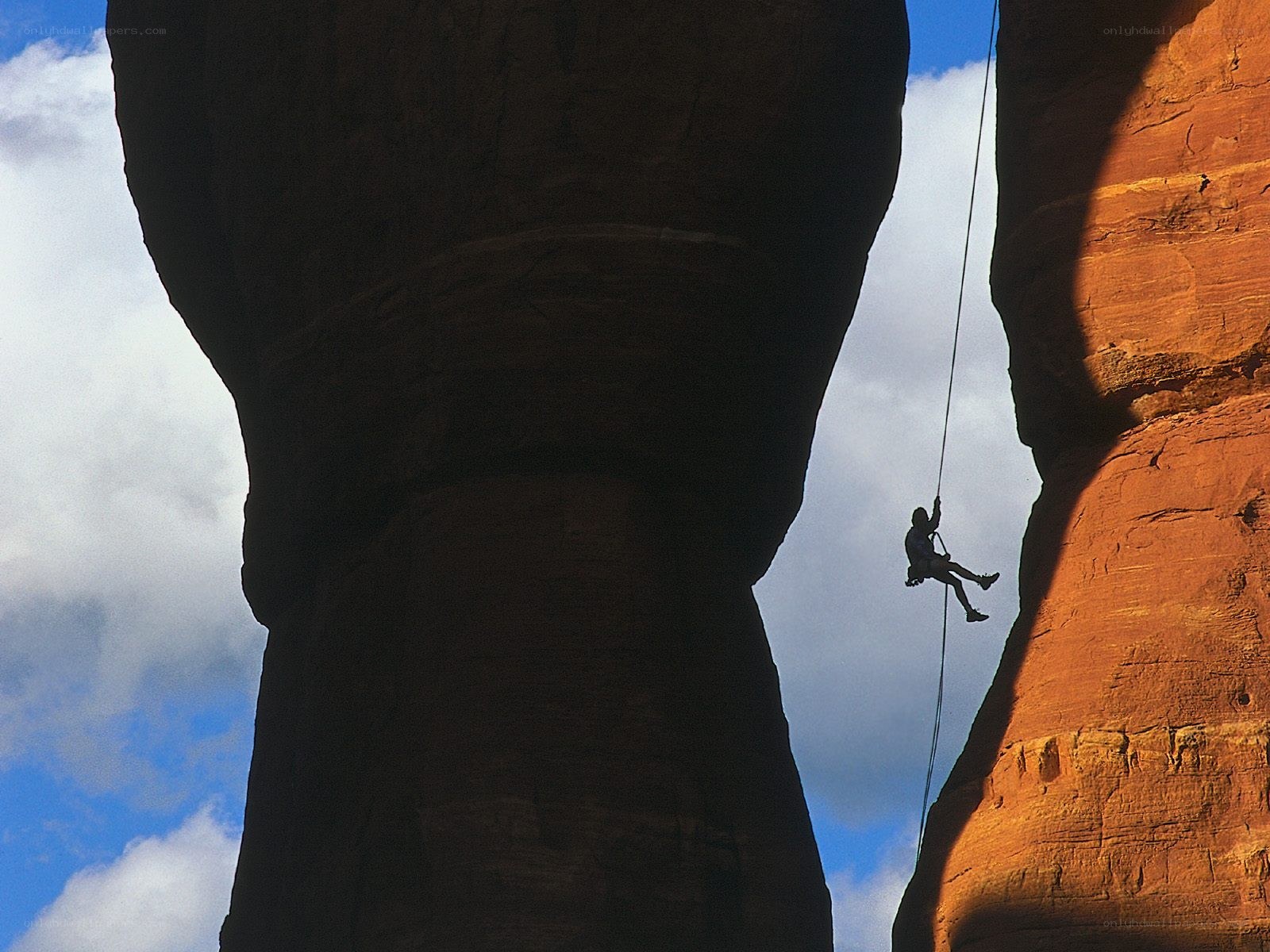Climber rappelling in canyon
