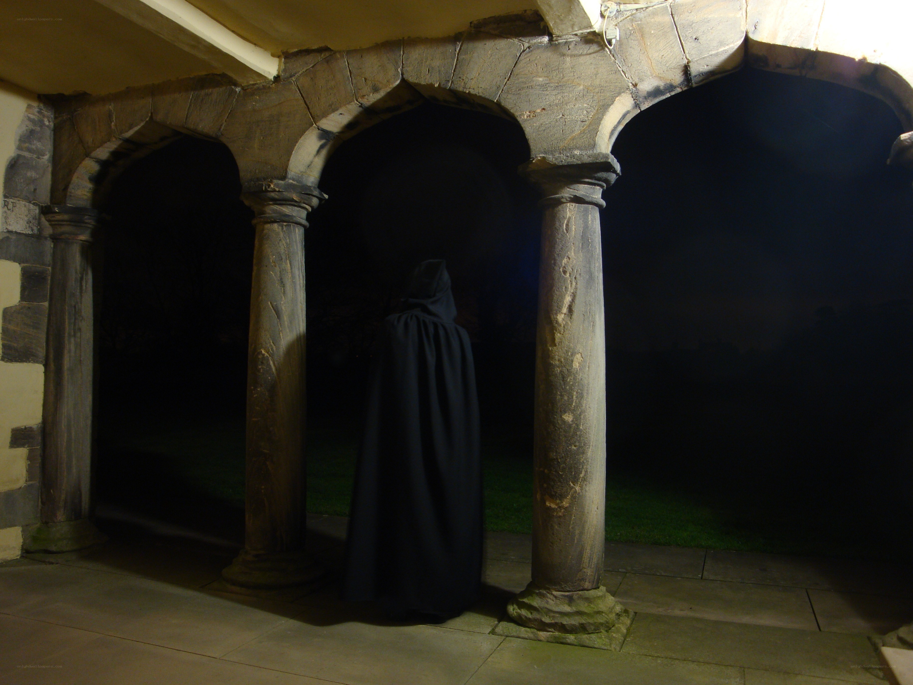 Cloaked figure in stone archway