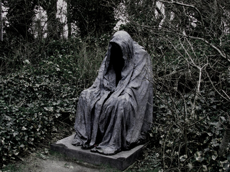 Cloaked figure statue in forest