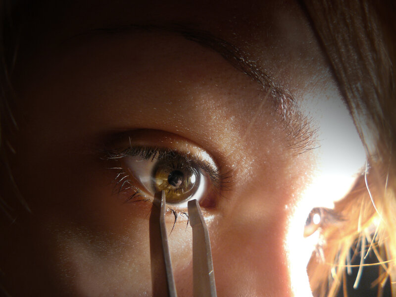 close-up of eye with tweezers