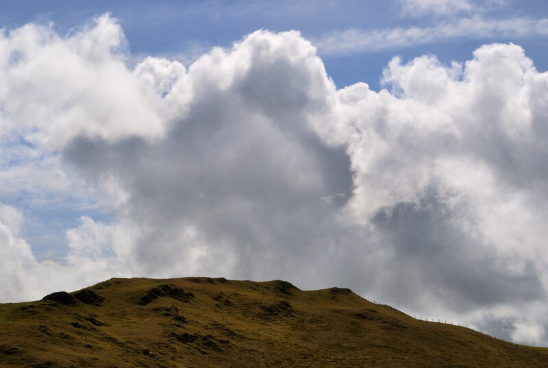 Clouds over a grassy hill