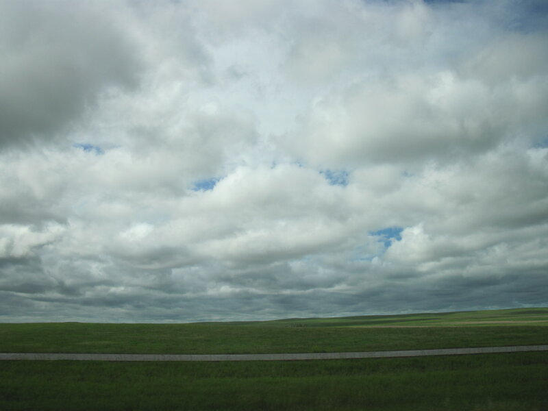 Cloudy sky over green fields