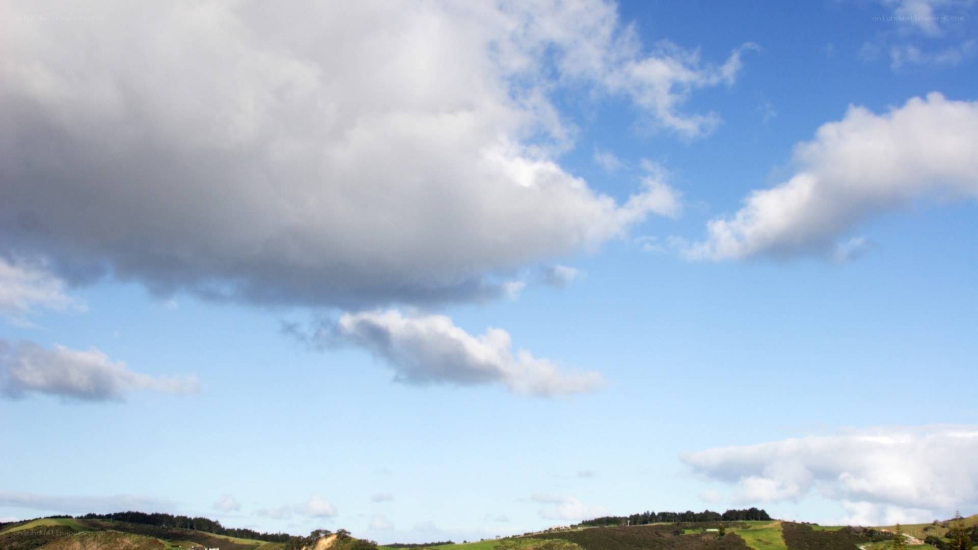 Cloudy sky over green hills