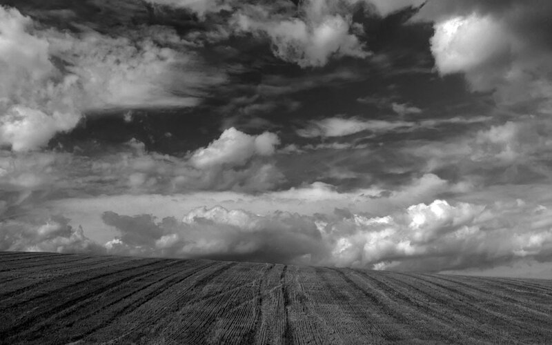 Cloudy sky over plowed field