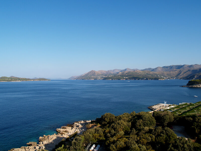 Coastal Bay with Mountains — Blue, Serene, Afternoon, Photograph, Sea, Trees, Dock