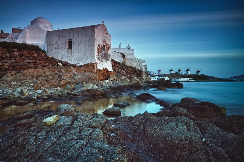 Coastal church and windmills at dusk