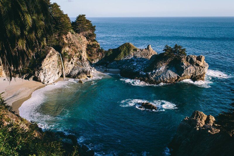 Coastal Cove with Waterfall — Blue, Serene, Afternoon, Photograph, Palm Trees