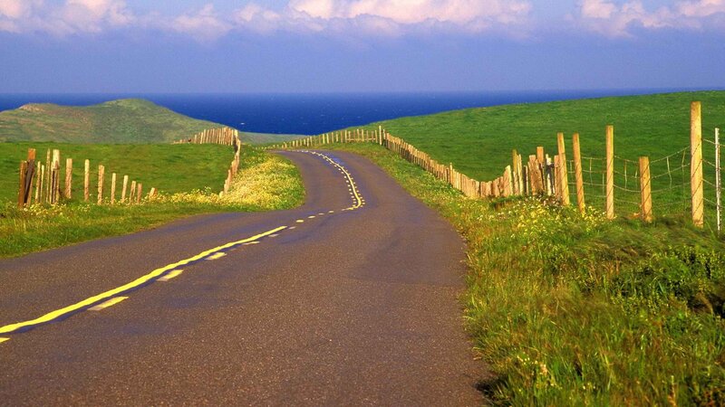 Coastal road winding through green hills