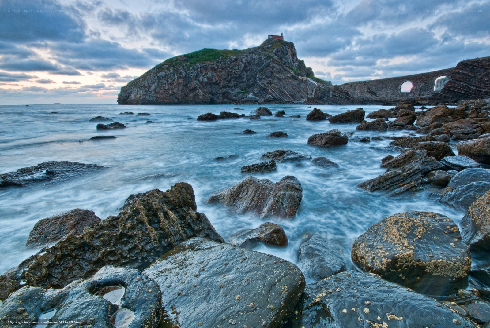 Coastal rocks and lighthouse at dusk