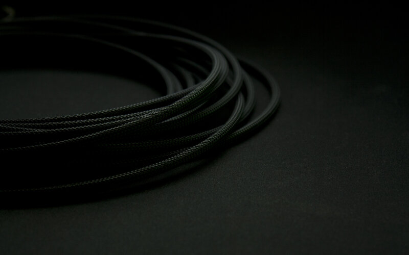 coiled black cable on dark surface
