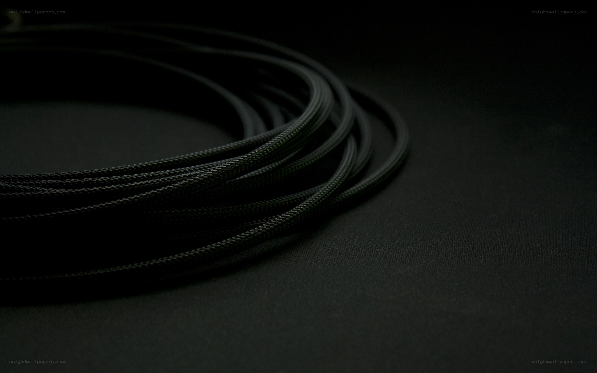 coiled black cable on dark surface