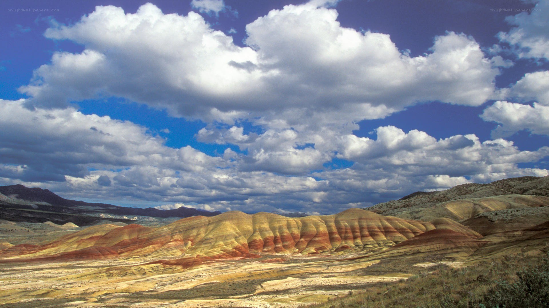 colorful badlands under cloudy sky