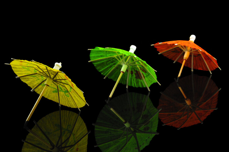 Colorful cocktail umbrellas on black