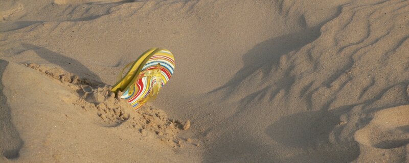 Colorful flip-flop on sandy beach