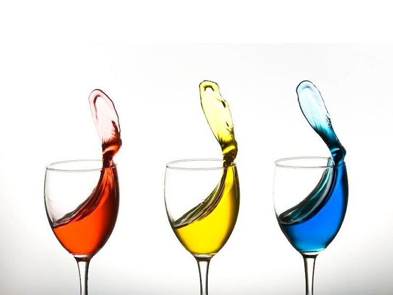 Colorful liquid splashing in wine glasses