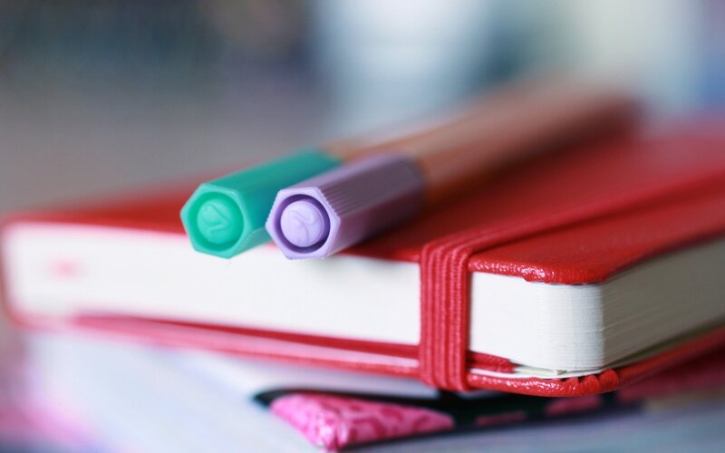 Colorful pens on red notebook