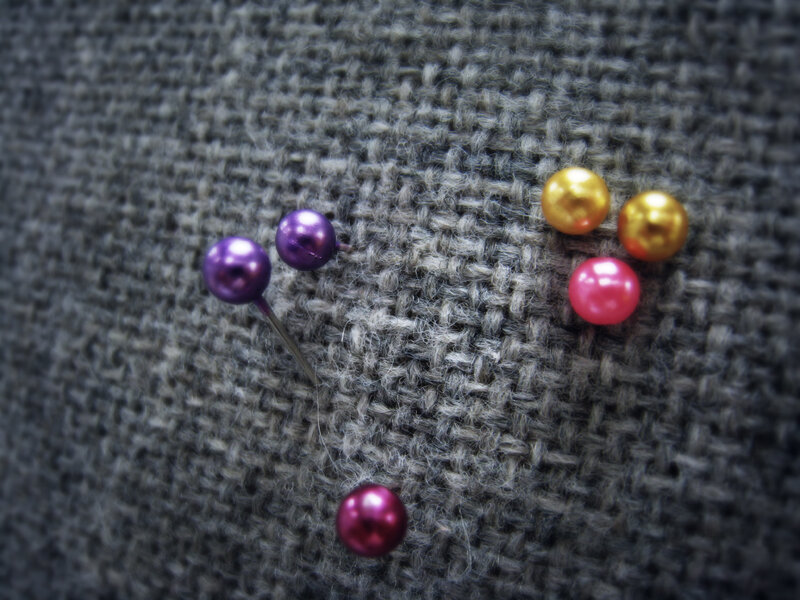 Colorful pins on gray fabric