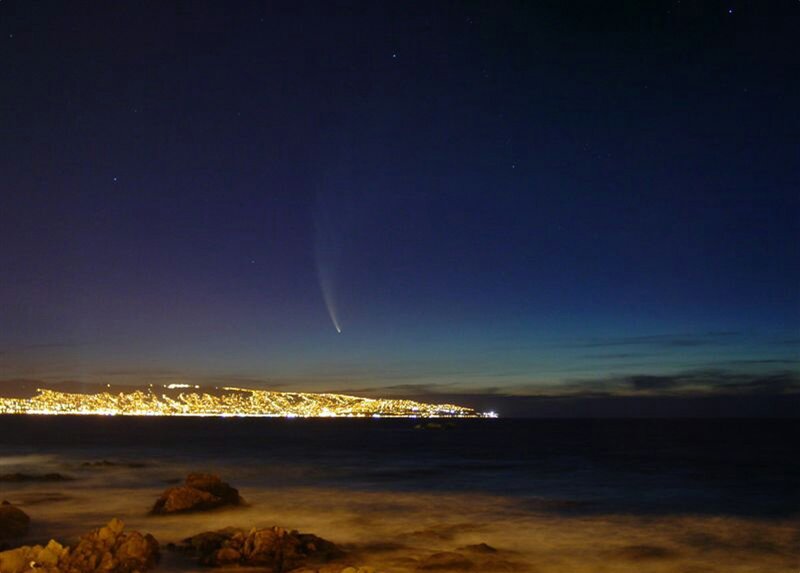 Comet over coastal city at night