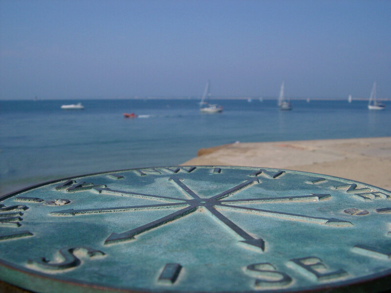 Compass on a beach with boats