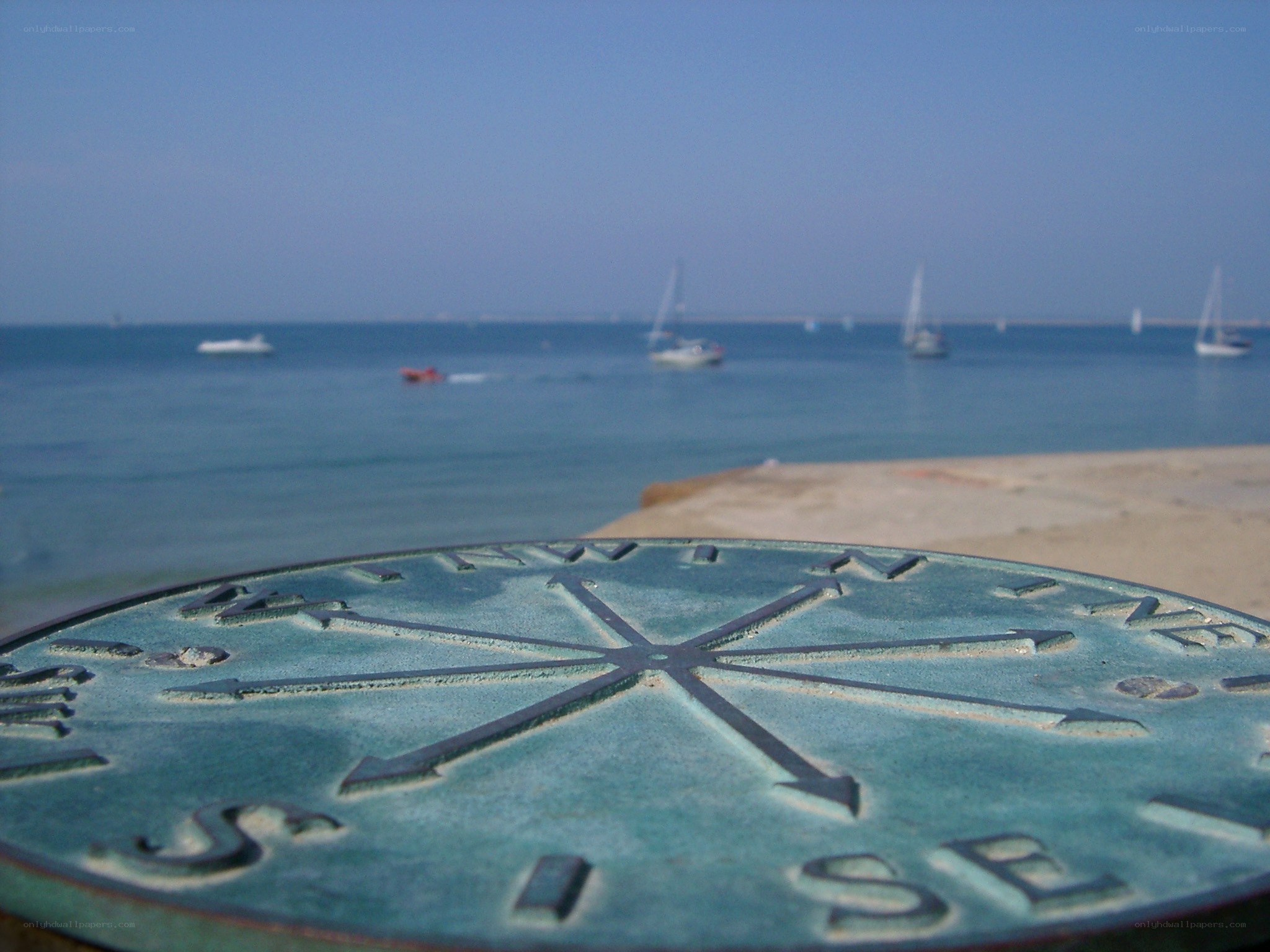 Compass on a beach with boats
