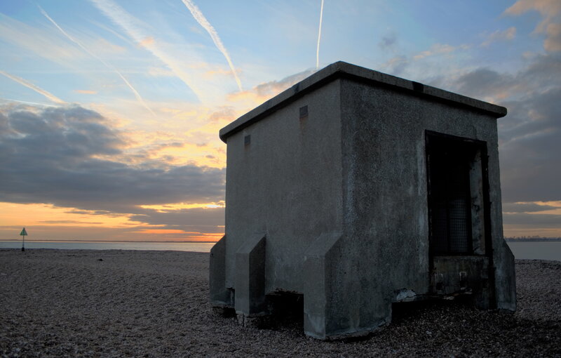 Concrete bunker on beach at sunset