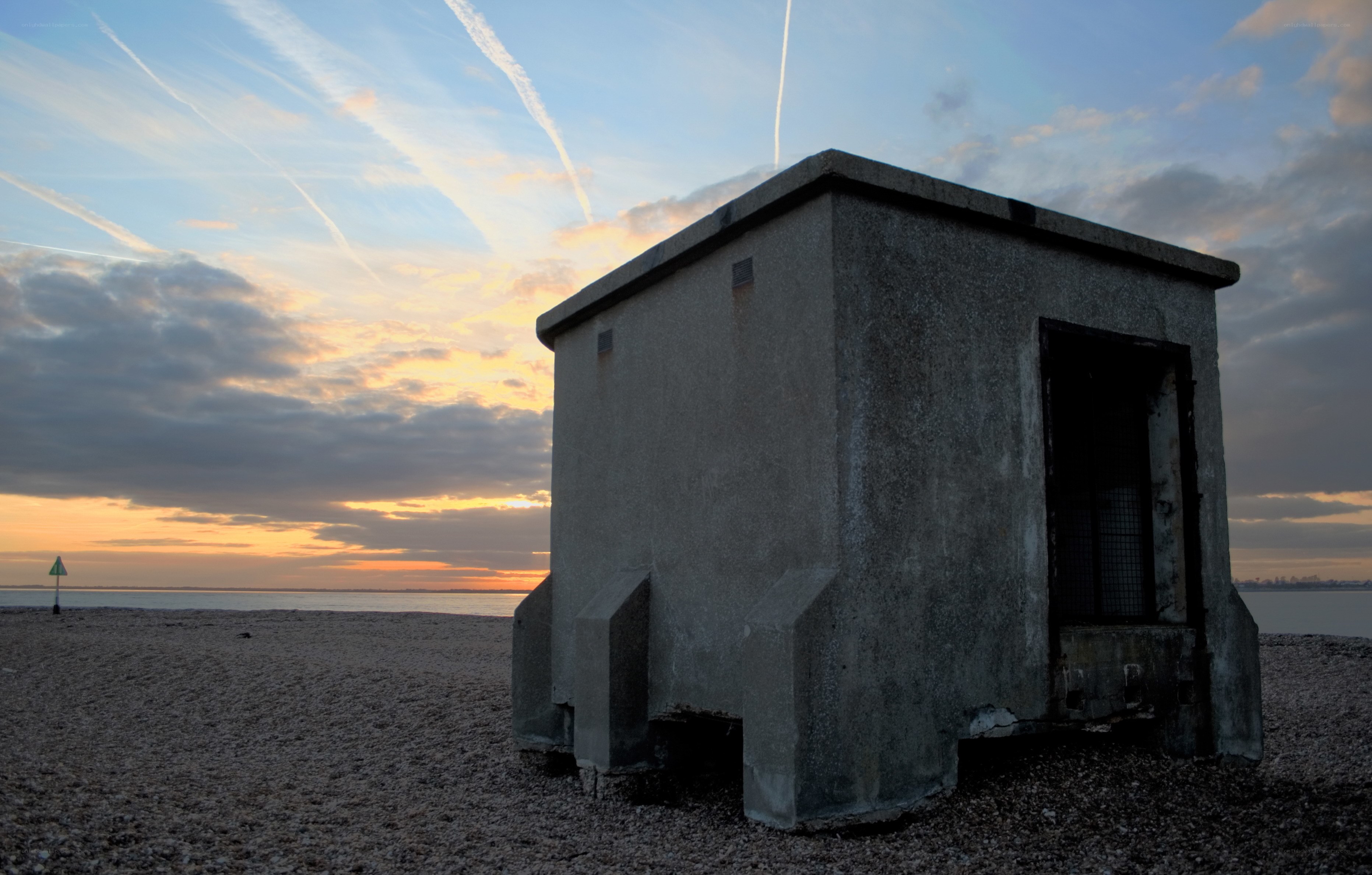 Concrete bunker on beach at sunset