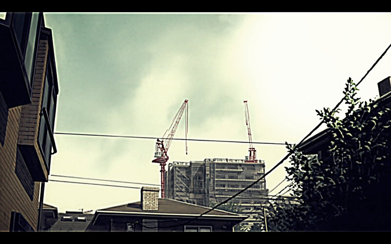 Construction cranes over city rooftops