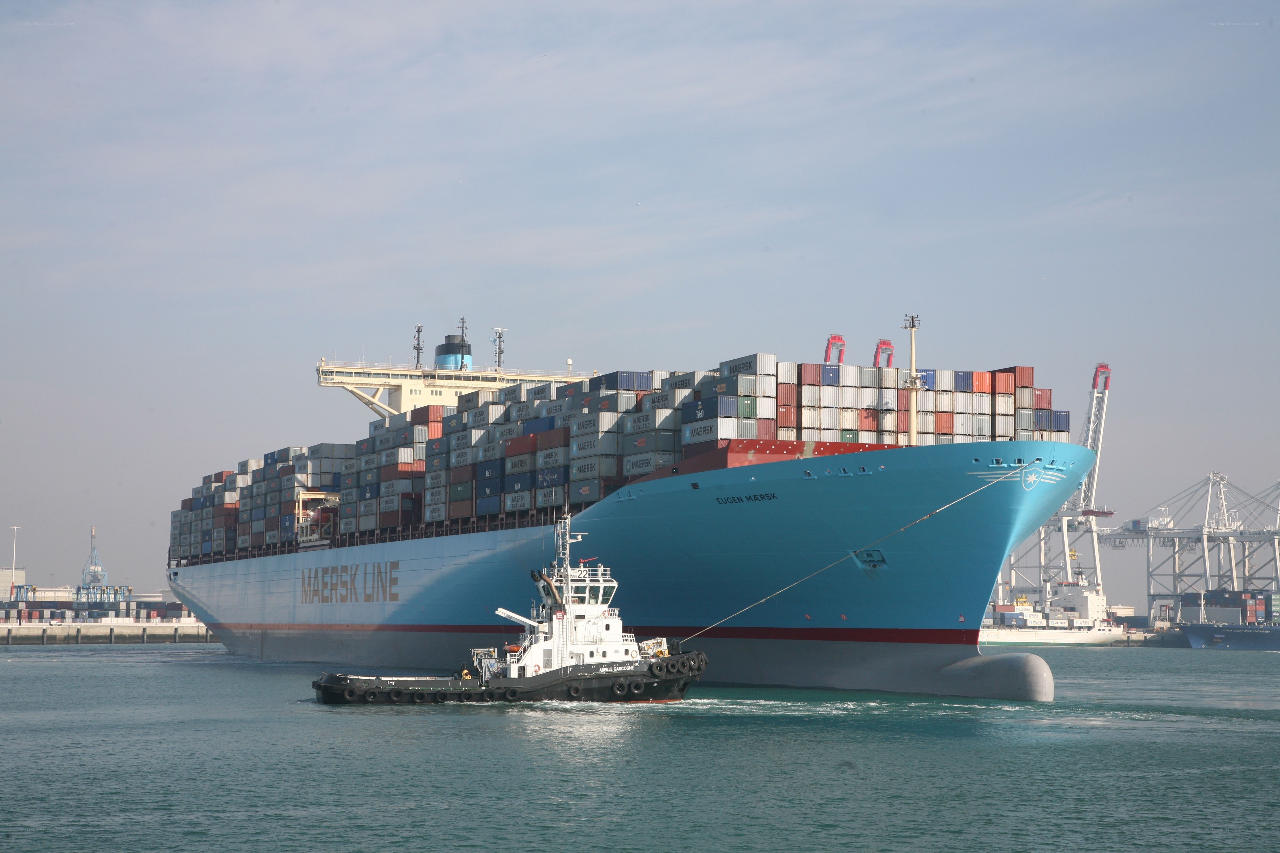 Container ship being guided by tugboat