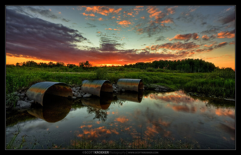 Corrugated Pipes in Stream — Orange, Dramatic, Sunset, Photograph, Sky