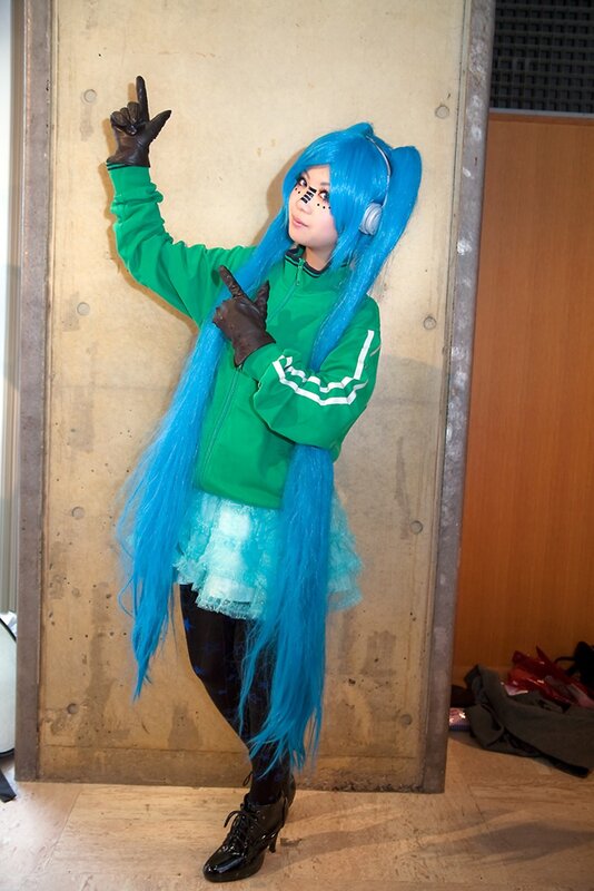 cosplayer in blue wig and green jacket